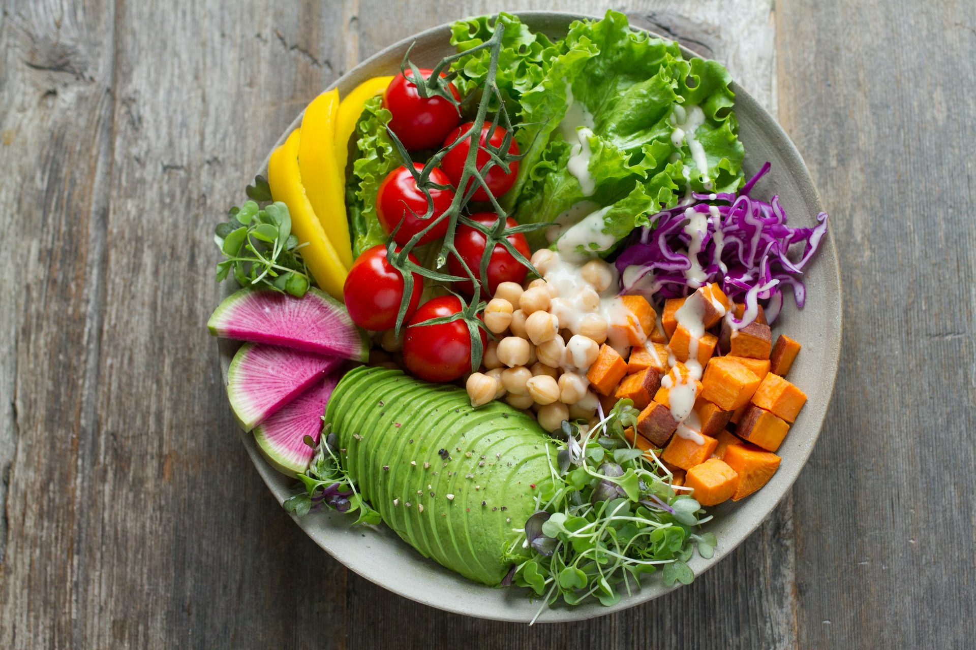 Bowl of salad with avocado, tomatoes, chickpeas, sweet potato and red cabbage
